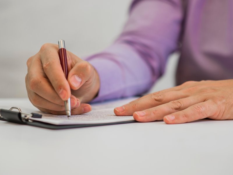 Young man holding a pencil, writing on a paper in the diary